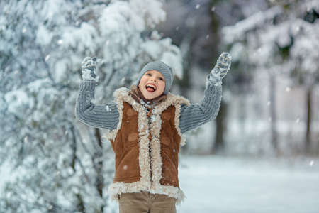 Happy boy playes on snowy winter day in the park. Kid is joy and happy . Child playing with snow in winter.の写真素材