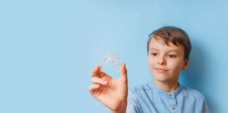 Night-guard case selective focus. Helps equalize the growing teeth and correct bite, banner. Portrait of the boy with orthodontic silicone trainer. Mobile orthodontic appliance for dental correction.の写真素材