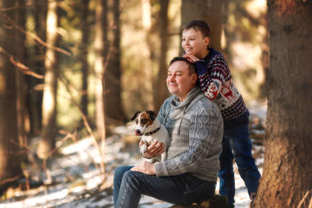 Happy family - father and son sitting with dog on autumn forest glade. Fathers day.の写真素材