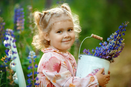 Portrait of a pretty blonde girl with bouquets of lupins in the bucketの写真素材
