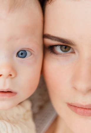 Close up portrait of son and mother. Face to face, hulf face. Moyher has a green eye and son has a blue eye. Genetics, generation concept.の写真素材