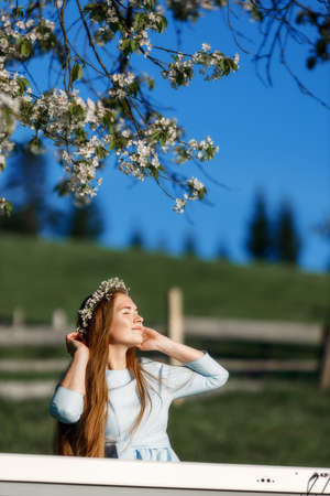 Girl playing a synthesizer piano in nature at sunset. A woman is touching hair and enjoying the sun. An electric piano stands in a field in a village. Spring day in the countryside.の写真素材