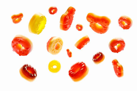 Close up of sweet orange, red and yellow jelly donuts set isolated on white background. Chewy gummy candies are falling from the topの写真素材