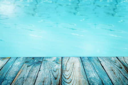 Perspective wood table top and blue water abstract background, product display montage. Empty wooden...