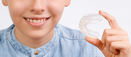 Positive child boy is holding mouth guards for his teeth and smiling. Banner. Invisible braces helps...
