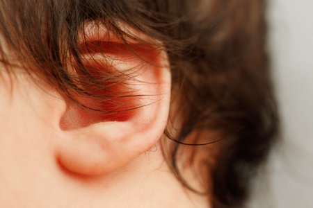 Close-up macro shot of a newborn baby tiny ear and soft dark hair, showing delicate skin and natural baby features.の写真素材