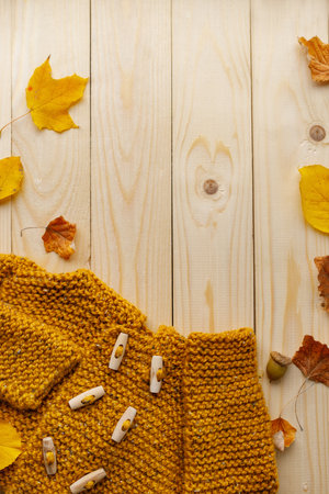 Top view composition featuring a knitted yellow cardigan with wooden buttons, surrounded by colorful...