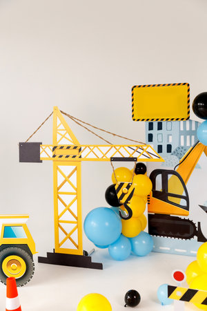 Colorful construction-themed kids party decoration with excavator and crane cutouts, balloons, cones, caution tape, and playful props, perfect for children birthday celebration or photo backdrop.の写真素材