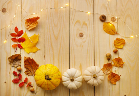 A vibrant and natural autumn flat lay featuring a small yellow decorative pumpkin and two small...