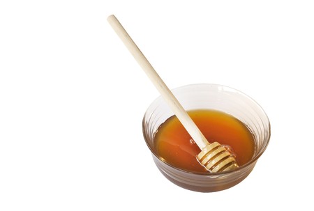 Glass bowl and wooden spoon with honeyの写真素材