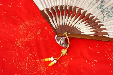 Open chinese silk fan on red paperの写真素材