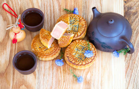 Traditional chinese moon cakes on board for mid autumn festival. Hieroglyphs on moon cakes mean the components of their inner filling - crystal sugar, rose hip, gold wire, fine sand, date.の写真素材
