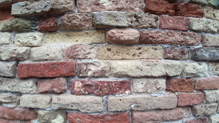 Background of a grunge old stone wall with colored bricksの写真素材
