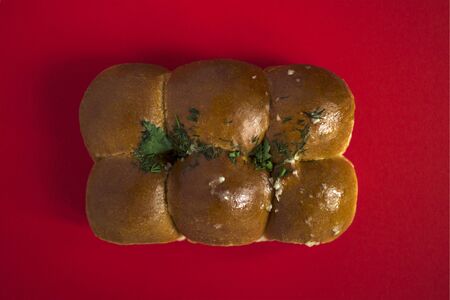 Ukrainian national food. Pampushki with garlic and herbs for borsch on a red background. Bread...