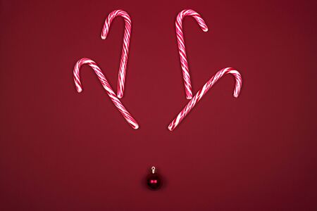 Christmas Reindeer concept, horns of striped lollipops sticks and Christmas ball. Top view composition, flat lay. Cute surreal face deer.の写真素材
