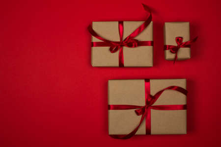 Gift box set on a red background. Satin burgundy ribbon, bow, box wrapped in craft paper. Luxury...