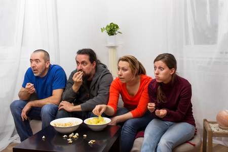 Four friends watching an exciting movie on TV
