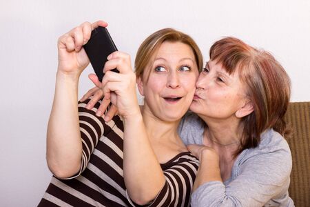 Mother and daughter having fun taking some selfiesの写真素材