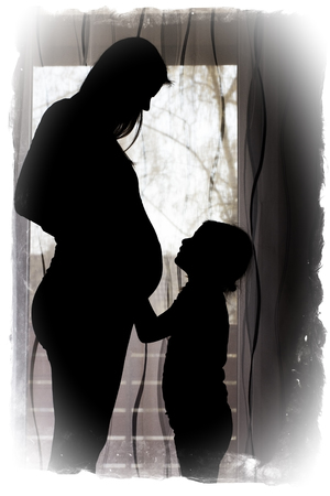 Silhouette of a pregnant woman with her childの写真素材