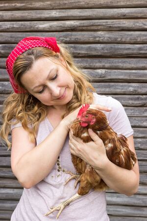 Young farmer holding a hen in her armsの写真素材