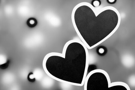Several black hearts photographed against a lit background photographed in black and whiteの写真素材