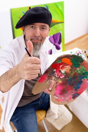 Painter sitting in front of an easel and looking at the cameraの写真素材