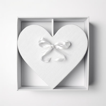 White heart shaped gift box with bow on white background. Top view.の写真素材