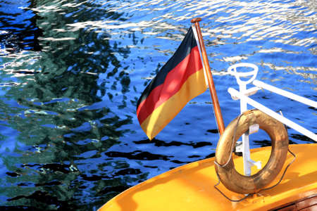 The picture shows the stern of a yellow sailboat with a German flag and the safety ring in Hamburg harbour.の写真素材