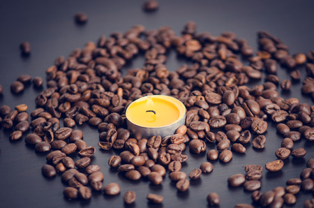 Coffee beans on a black background with candle. Raw coffee beans and fire from candle. Grained product. Hot drink. close upの写真素材
