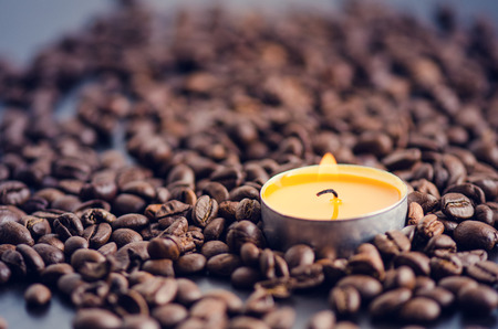 Coffee beans on a black background with candle. Raw coffee beans and fire from candle. Grained product. Hot drink. close upの写真素材