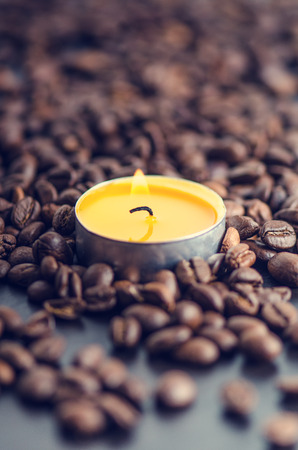 Coffee beans on a black background with candle. Raw coffee beans and fire from candle. Grained product. Hot drink. close upの写真素材