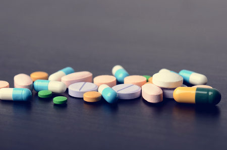 Pharmacy background on a black table. Tablets on a black background. Pills. Medicine and Health. Close up of capsules. Differend kind of pillsの写真素材