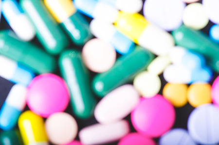Blurry pharmacy background on a black table. Tablets on a black background. Pills. Medicine and Health. Close up of capsules. Differend kind of pillsの写真素材