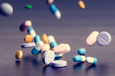 Pharmacy background on a dark table. Levitation pills. Tablets on a dark background Which falling down. Pills. Medicine and Health. Close up of capsules. Differend kind of pillsの写真素材