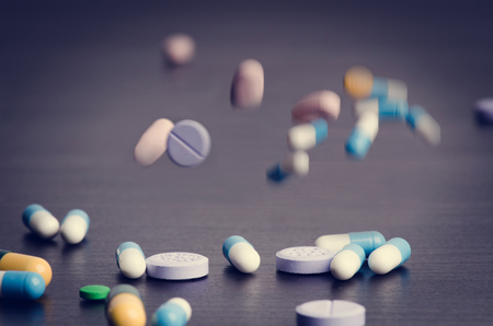 Pharmacy background on a dark table. Levitation pills. Tablets on a dark background Which falling down. Pills. Medicine and Health. Close up of capsules. Differend kind of pillsの写真素材