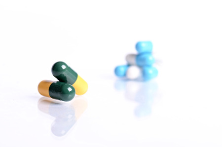Tablets isolated on a white background. Reflection of pills on a glass. Medicine's background. Pharmacy. Close up of capsules.の写真素材
