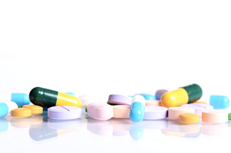 Tablets isolated on a white background. Reflection of pills on a glass. Medicine's background. Pharmacy. Close up of capsules.の写真素材