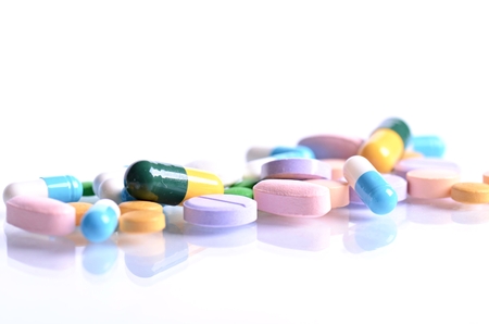 Tablets isolated on a white background. Reflection of pills on a glass. Medicine's background. Pharmacy. Close up of capsules.の写真素材