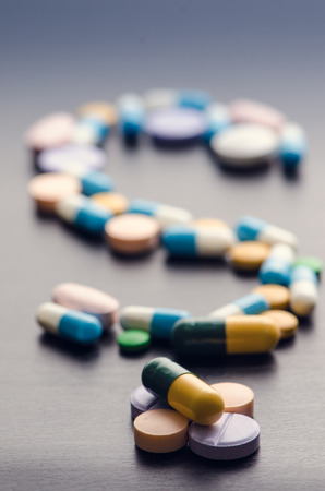 Pharmacy background on a black table.Question. question mark. Tablets on a black background. Pills. Medicine and Health. Close up of capsules. Differend kind of pillsの写真素材
