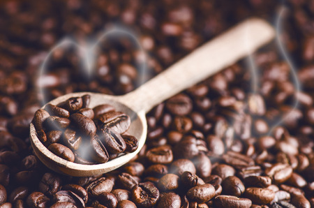 Spoon of coffee beans. Background. Energy. Raw coffee beans. Grained product. Hot drink. Close up. Harvesting. Natural background. Lifestyle. Coffee break in a morning. Wooden spoon. Steamの写真素材