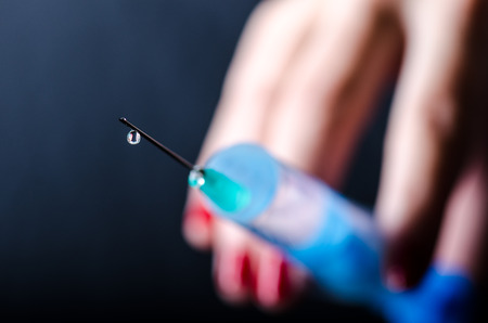 Medical injection on dark background. Medicine plastic vaccination equipment with needle. Health and care. Vaccination. Medicine background. Studio isolated. Phobia, Woman hand keep a injectionの写真素材