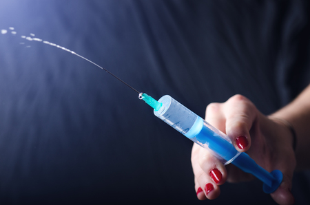 Medical injection on dark background. Medicine plastic vaccination equipment with needle. Health and care. Vaccination. Medicine background. Studio isolated. Phobia, Woman hand keep a injectionの写真素材