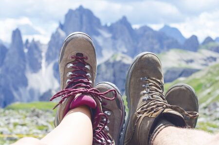 Man hiker lie on a ground. Peaks like a background. Sunny day.Trekking boots.Lens flare. Succesful backpacker enjoy a view.の写真素材