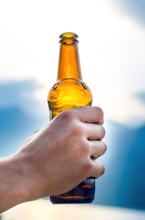 Bottle of beer. Natural background. Man hand´s keep a bottle of beer. Alcohol drink.の写真素材