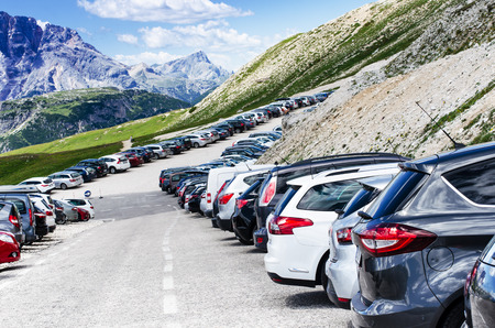 Cars in a parking lot in a middle of mountains. Vehicles on a beautiful sunshine. Transportation backgroundの写真素材