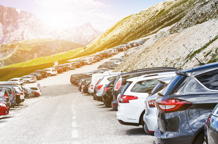 Cars in a parking lot in a middle of mountains. Vehicles on a beautiful sunshine. Transportation backgroundの写真素材