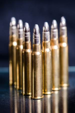 Ammunition on a dark blue background with reflection in a glass. Close up. Weapons. Bulletsの写真素材