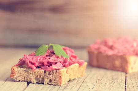 Two slices of bread on a wooden table with beetroot spread. Natural background and healthy, vegetarian and vegan food. Fast breakfast. Raw food. Agricultureの写真素材