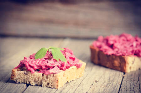Two slices of bread on a wooden table with beetroot spread. Natural background and healthy, vegetarian and vegan food. Fast breakfast. Raw food. Agricultureの写真素材