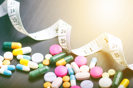 Pharmacy background on a black table with measuring tape. Tablets on a black background. Pills. Medicine and healthy. Close up of capsules. Differend kind of pillsの写真素材